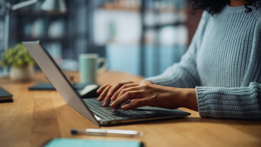 Close Up on Hands of a Female Specialist Working on Laptop Computer at Home faxing via her computer.